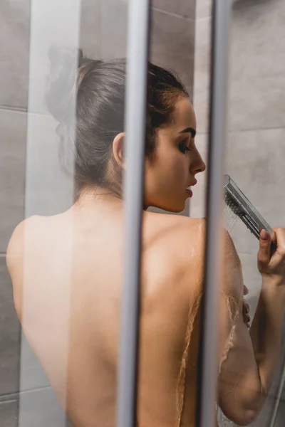 Вид сзади красивой женщины, принимающей душ в кабине — стоковое фото