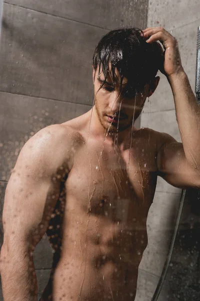 Голый и брюнетка мужчина принимает душ в кабине — стоковое фото