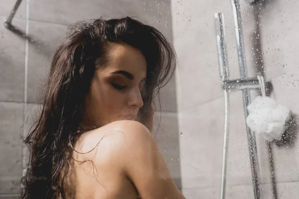 Brünette und nackte Frau unter der Dusche in der Kabine — Stockfoto