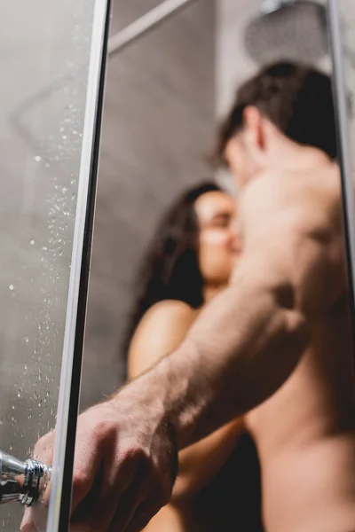 Messa a fuoco selettiva dell'uomo che tiene la maniglia e abbraccia con la donna in cabina doccia — Foto stock