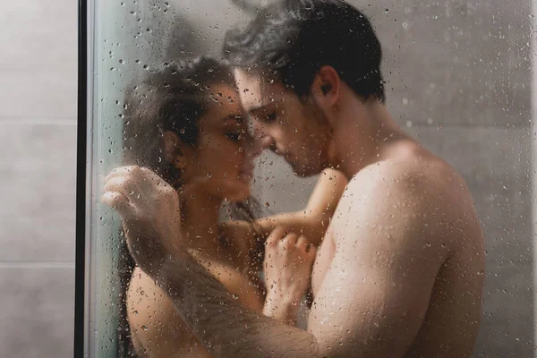 Enfoque selectivo de hombre sexy y hermosa mujer abrazándose en cabina de ducha - foto de stock
