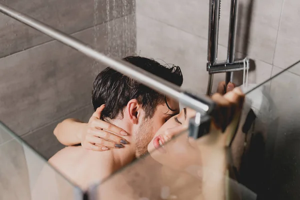 Nu homem e bela mulher abraçando e beijando no chuveiro cabine — Fotografia de Stock