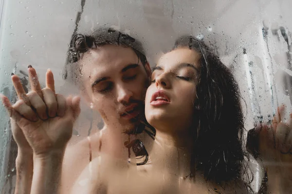Enfoque selectivo de apasionado hombre desnudo y atractiva mujer abrazándose en cabina de ducha - foto de stock