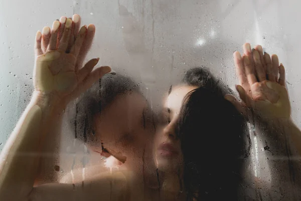 Вибірковий фокус пристрасного голого чоловіка цілує привабливу жінку в душовій кабіні — стокове фото