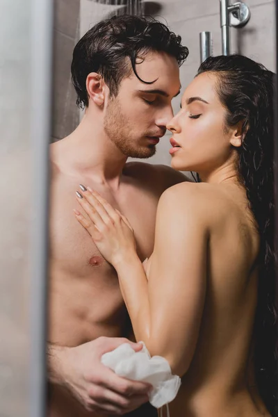 Sexy hombre desnudo y atractiva mujer abrazándose en cabina de ducha - foto de stock