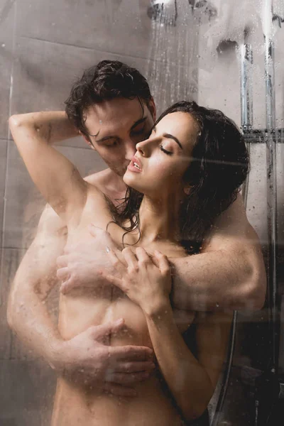 Naked handsome man and attractive woman hugging in shower cabin — Stock Photo