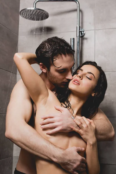 Passionate handsome man and attractive woman hugging in shower cabin — Stock Photo