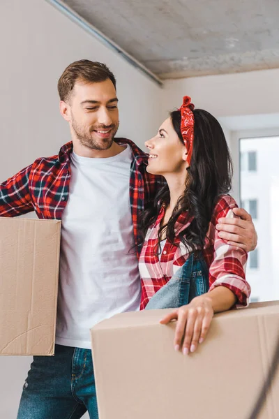 Guapo novio mirando novia holding caja en casa - foto de stock