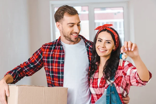 Handsome boyfriend looking at cheerful girlfriend holding keys at home — Stock Photo