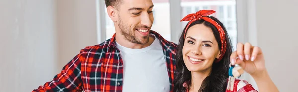 Happy boyfriend looking at cheerful girlfriend holding keys at home — Stock Photo