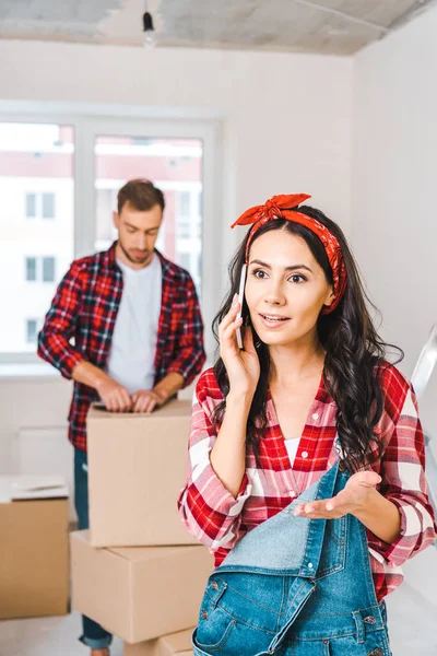 Foyer sélectif de la femme parlant sur smartphone près de petit ami à la maison — Photo de stock