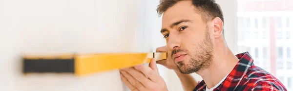 Homem sério que mede parede em casa — Fotografia de Stock