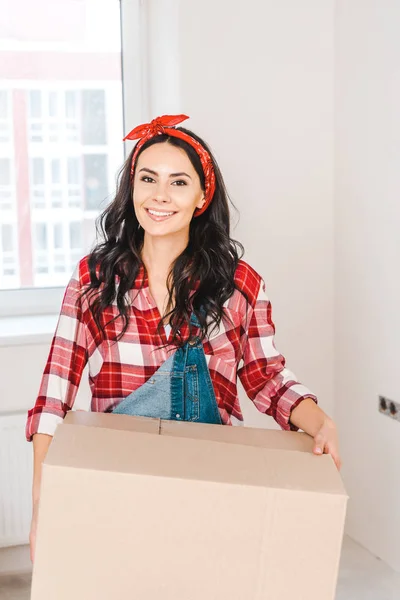 Mujer feliz sosteniendo caja y sonriendo en casa - foto de stock