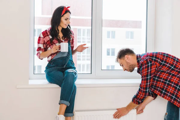 Atractiva mujer hablando con el novio mientras sostiene la taza en casa - foto de stock