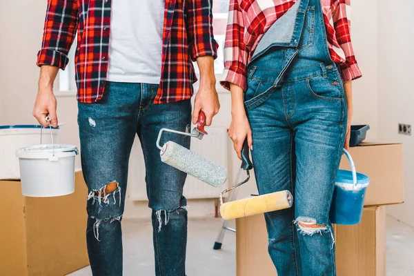 Vista cortada de casal segurando baldes de pintura e rolos em casa — Fotografia de Stock