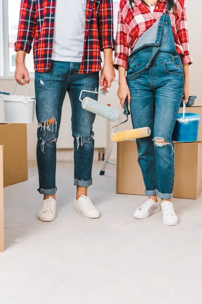 Cropped view of man and woman holding paint buckets and rollers at home — Stock Photo