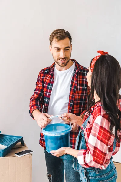 Mann nimmt Farbeimer und sieht Frau zu Hause an — Stockfoto