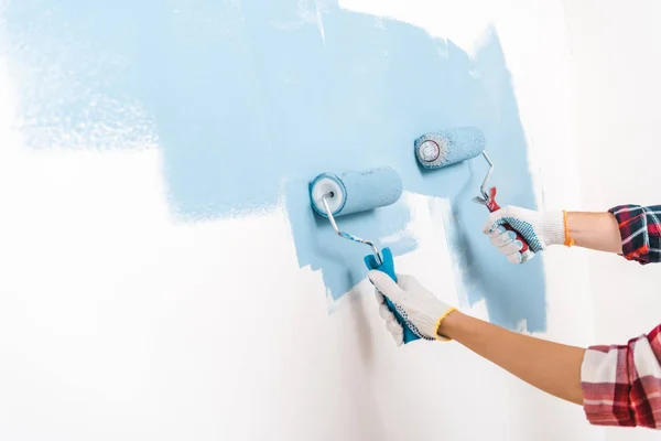 Corte vista de homem e mulher pintura parede na cor azul em casa — Fotografia de Stock