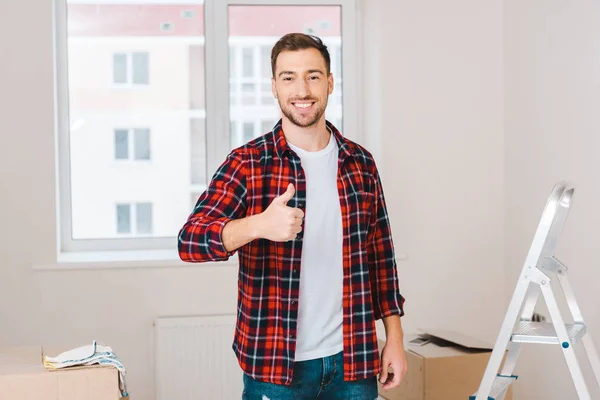 Uomo allegro mostrando pollice in su mentre in piedi a casa — Foto stock