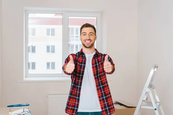 Happy man showing thumbs up while standing at home — Stock Photo