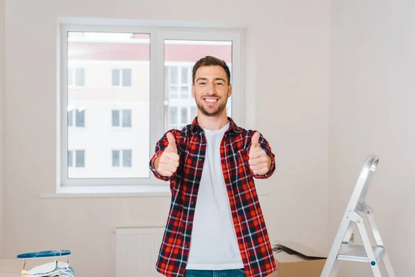 Homme heureux montrant pouces levés tout en se tenant à la maison — Photo de stock