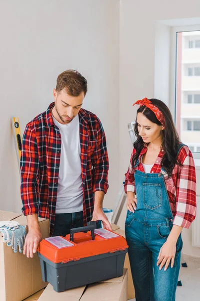 Couple looking at toolbox standing on boxes at home — Stock Photo