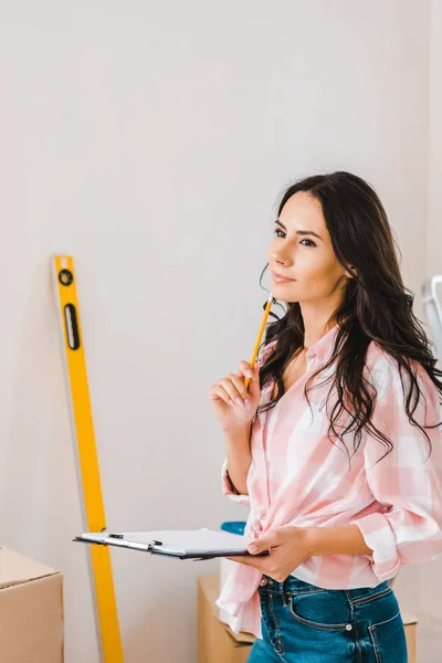 Atractiva mujer sosteniendo portapapeles y lápiz en las manos - foto de stock