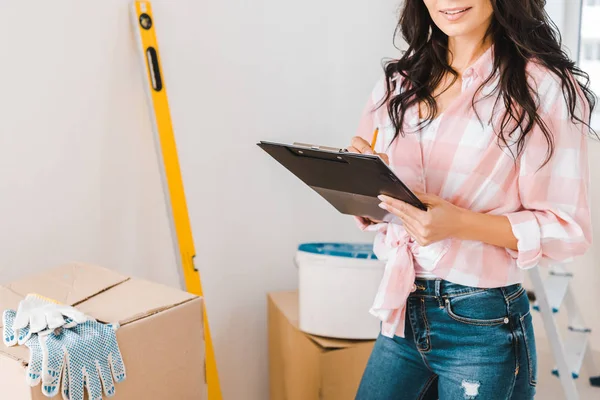 Cropped view of woman holding clipboard and pencil in hands — Stock Photo