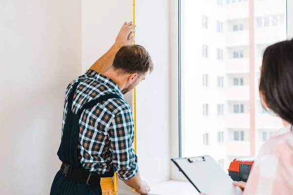 Foyer sélectif de bricoleur fenêtre de mesure près de client féminin — Photo de stock