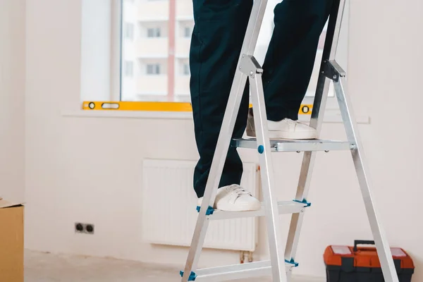 Cropped view of man standing on ladder in room — Stock Photo