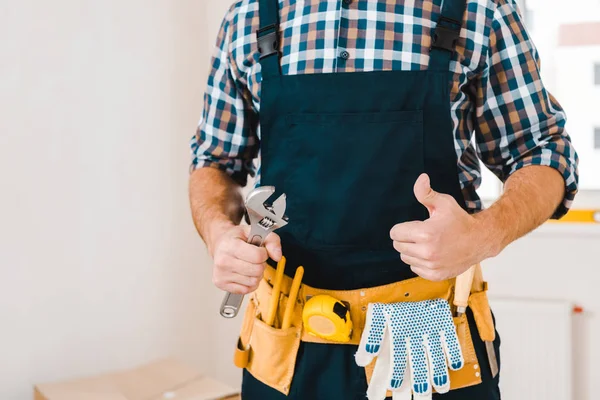 Vista cortada de handyman segurando chave e mostrando polegar para cima — Fotografia de Stock