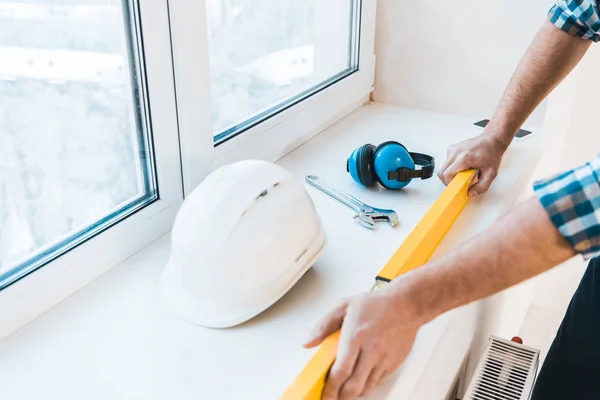 Cropped view of man holding measuring level near objects — Stock Photo