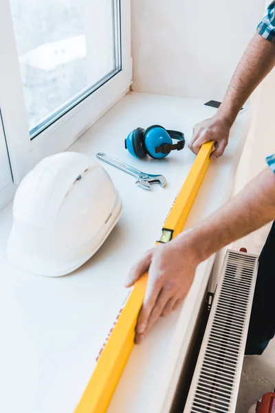 Vista cortada de handyman segurando nível de medição perto de objetos — Fotografia de Stock