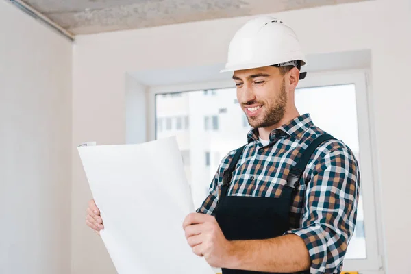Cheerful handyman smiling while looking at blueprint — Stock Photo