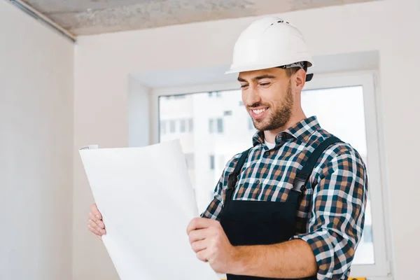 Fröhlicher Heimwerker lächelt beim Betrachten der Blaupause — Stockfoto