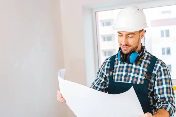 Happy handyman smiling while looking at blueprint — Stock Photo