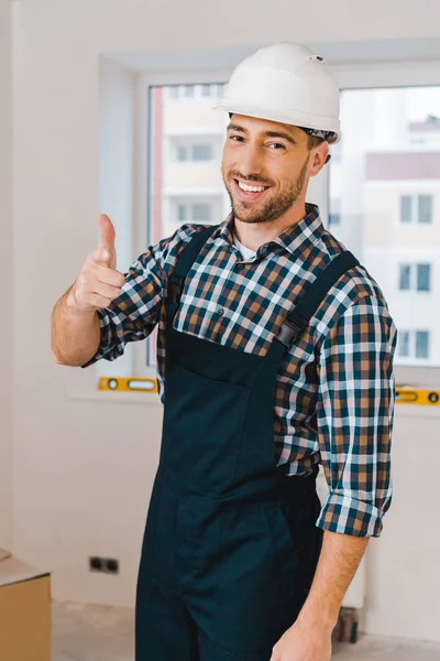 Bonito faz-tudo de pé e sorrindo enquanto mostrando polegar para cima — Fotografia de Stock