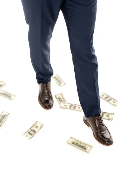 Vista recortada de hombre de negocios con billetes de dólar bajo los pies, aislado en blanco - foto de stock