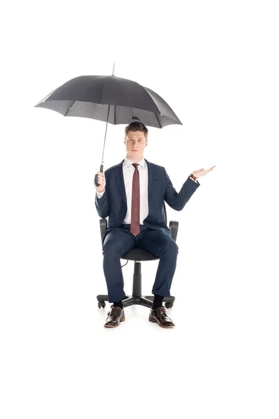 Confident businessman with umbrella sitting on chair and checking rain, isolated on white — Stock Photo