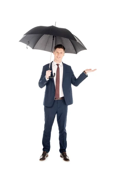 Sorridente empresário de terno com guarda-chuva verificando chuva, isolado em branco — Fotografia de Stock
