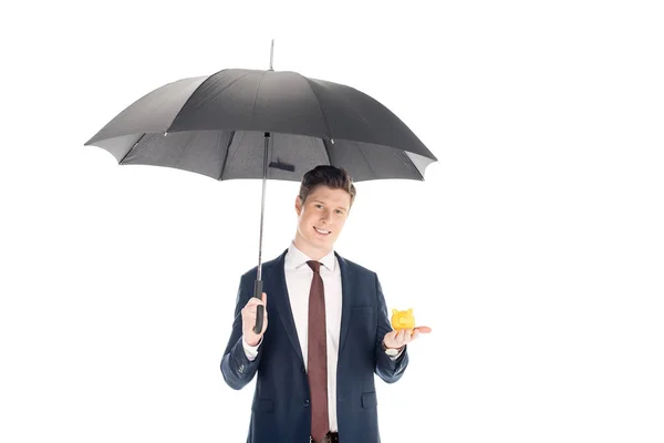 Lächelnder Geschäftsmann mit Regenschirm und kleinem Sparschwein auf weißem Grund — Stockfoto