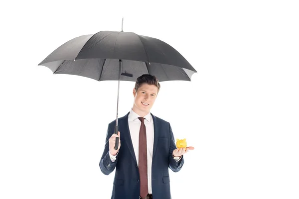 Smiling businessman with umbrella holding little piggy bank isolated on white — Stock Photo