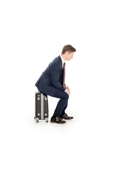 Бизнесмен, сидящий на багаже для деловой поездки, изолированный на белом — стоковое фото