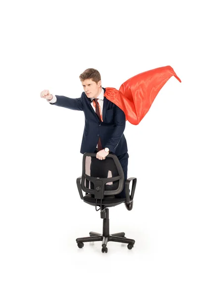 Super businessman in red cloak riding chair isolated on white — Stock Photo