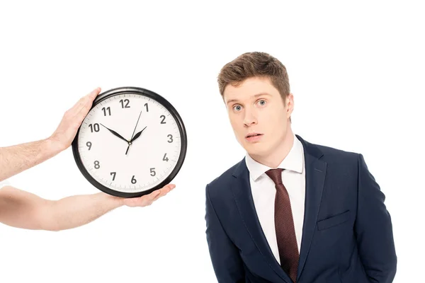 Person hält Uhr in der Nähe schöner junger Geschäftsmann isoliert auf weiß — Stockfoto