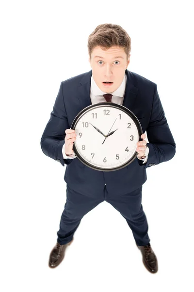 Schockierter gutaussehender Geschäftsmann hält Uhr isoliert auf weiß — Stockfoto