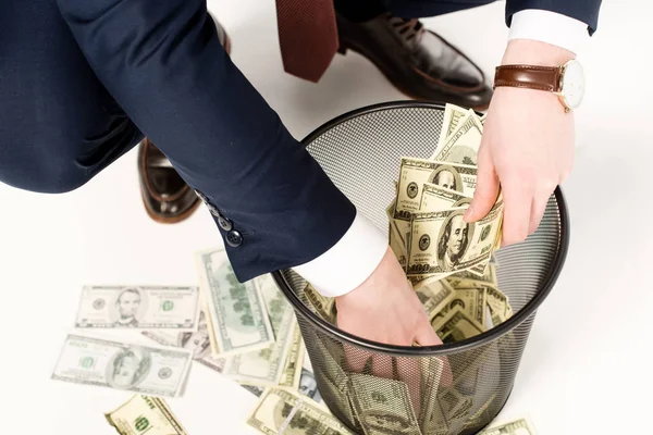 Vista recortada del hombre de negocios tomando billetes de dólar de la papelera en blanco - foto de stock