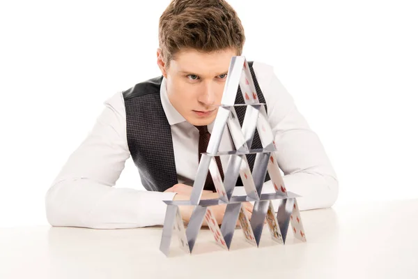 Homme concentré faisant pyramide à partir de cartes à jouer isolé sur blanc — Photo de stock