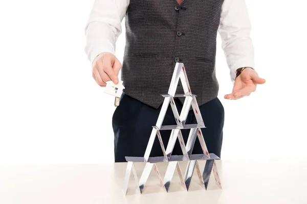 Обрізаний вид агента з нерухомості, який тримає ключі від нового будинку і показує піраміду з гральних карт, ізольовані на білому — стокове фото