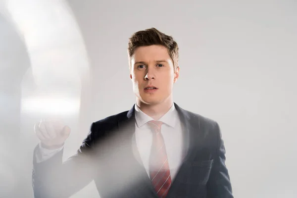 Selective focus of young businessman gesturing on grey — Stock Photo